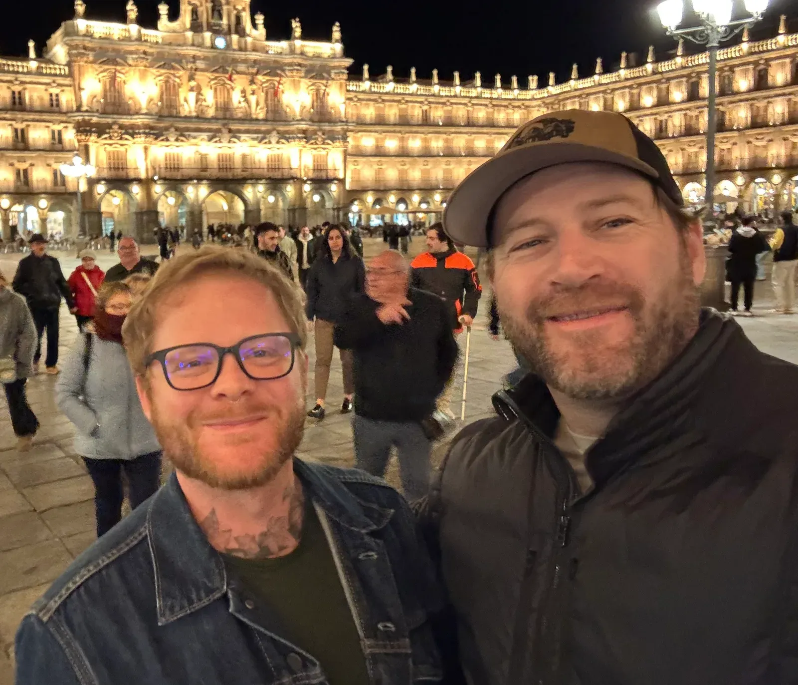 Shane and David today, taking a selfie in a lit-up city plaza at night